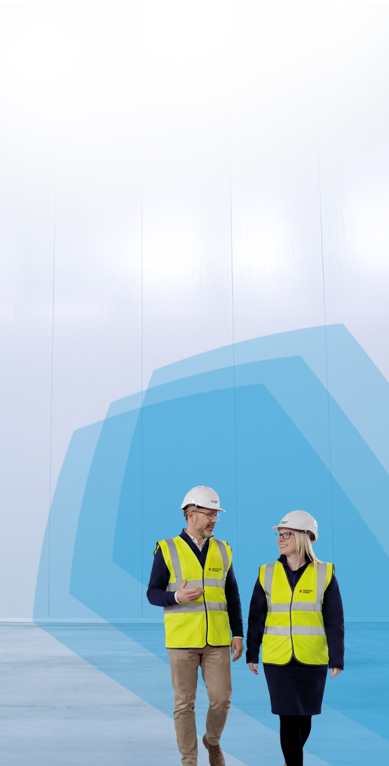 Two Engineers Talking, Walking Across Empty Factory Floor, Inspe